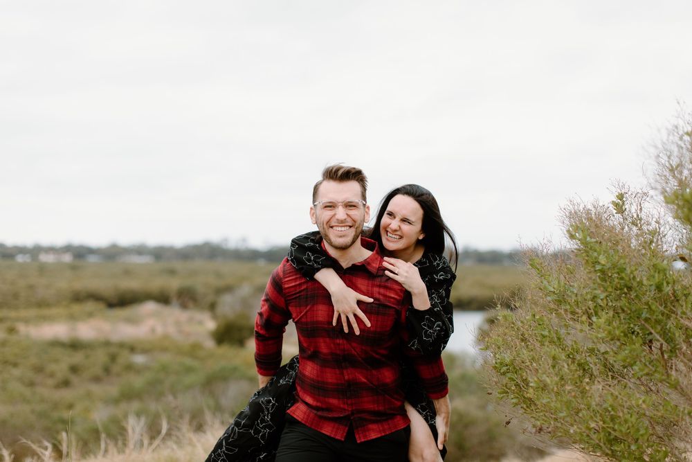Joyful couple enjoying piggyback ride in natural landscape.