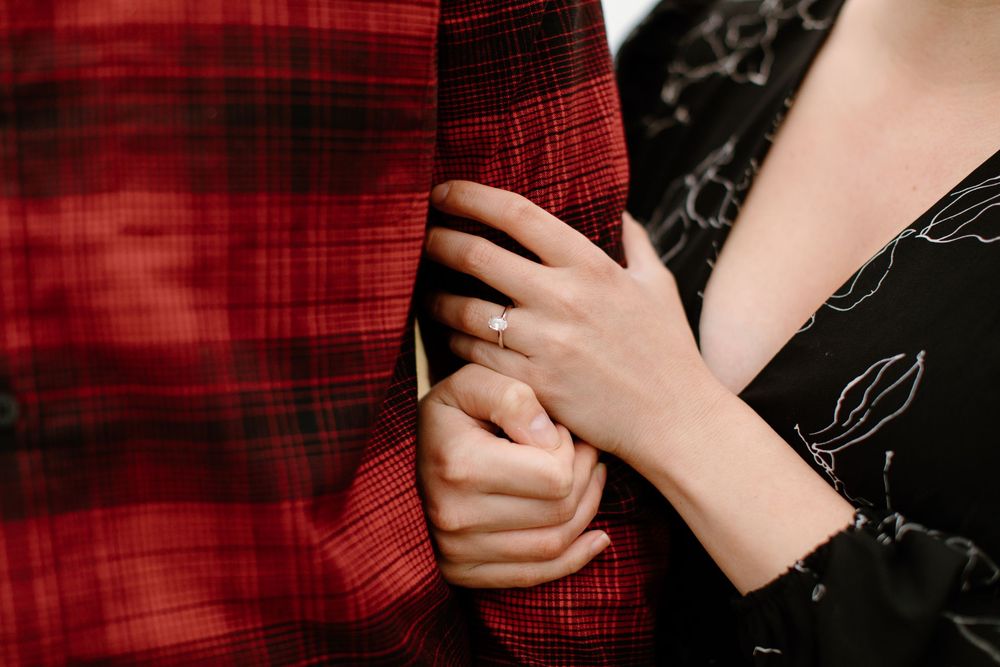 Close-up of hands holding against red plaid shirt and black floral dress.