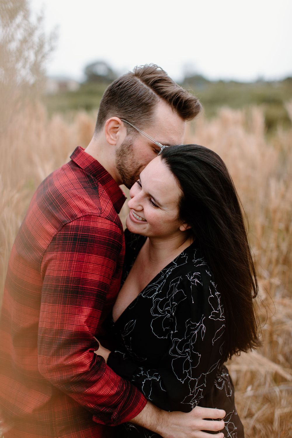 Intimate moment captured between couple in autumn field with warm lighting.