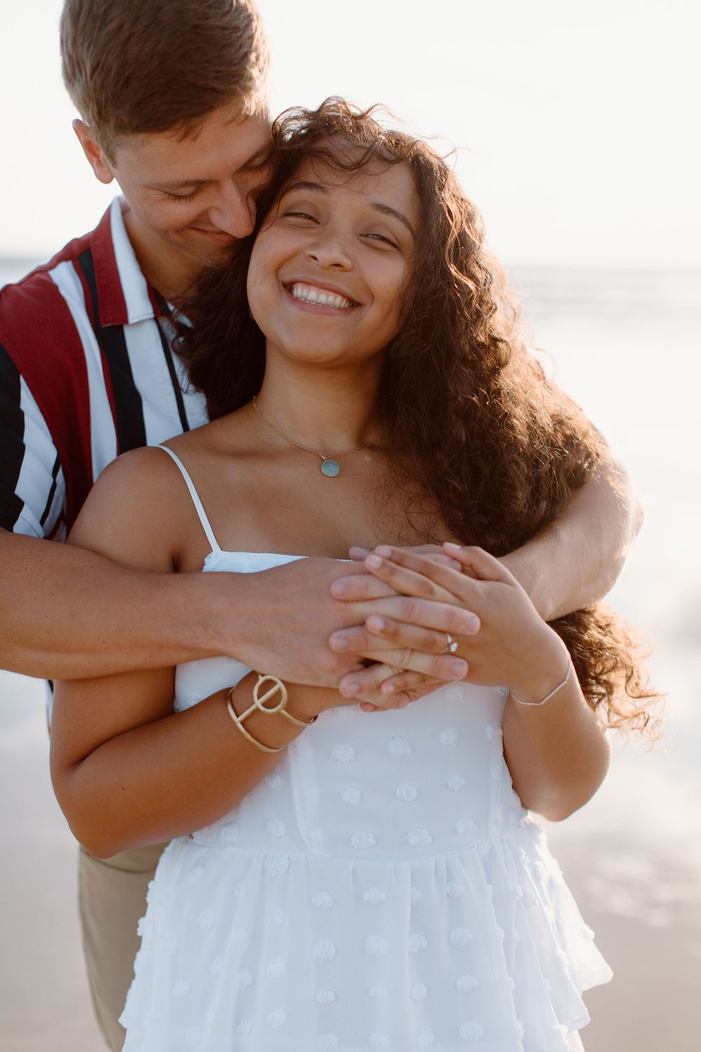 Intimate embrace on beach with couple sharing a joyful moment at sunset.