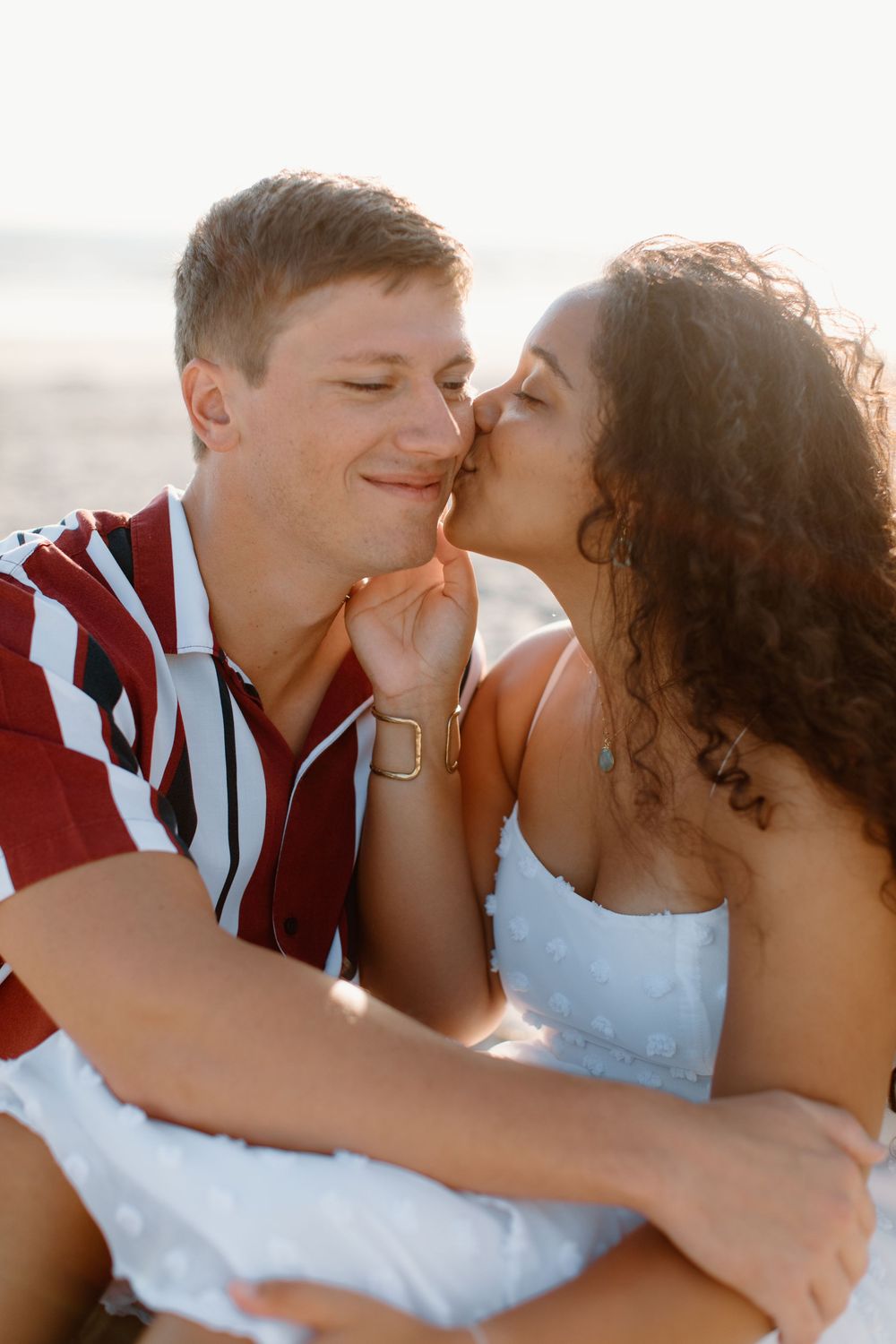 Romantic couple sharing an intimate moment at sunset on a beach.