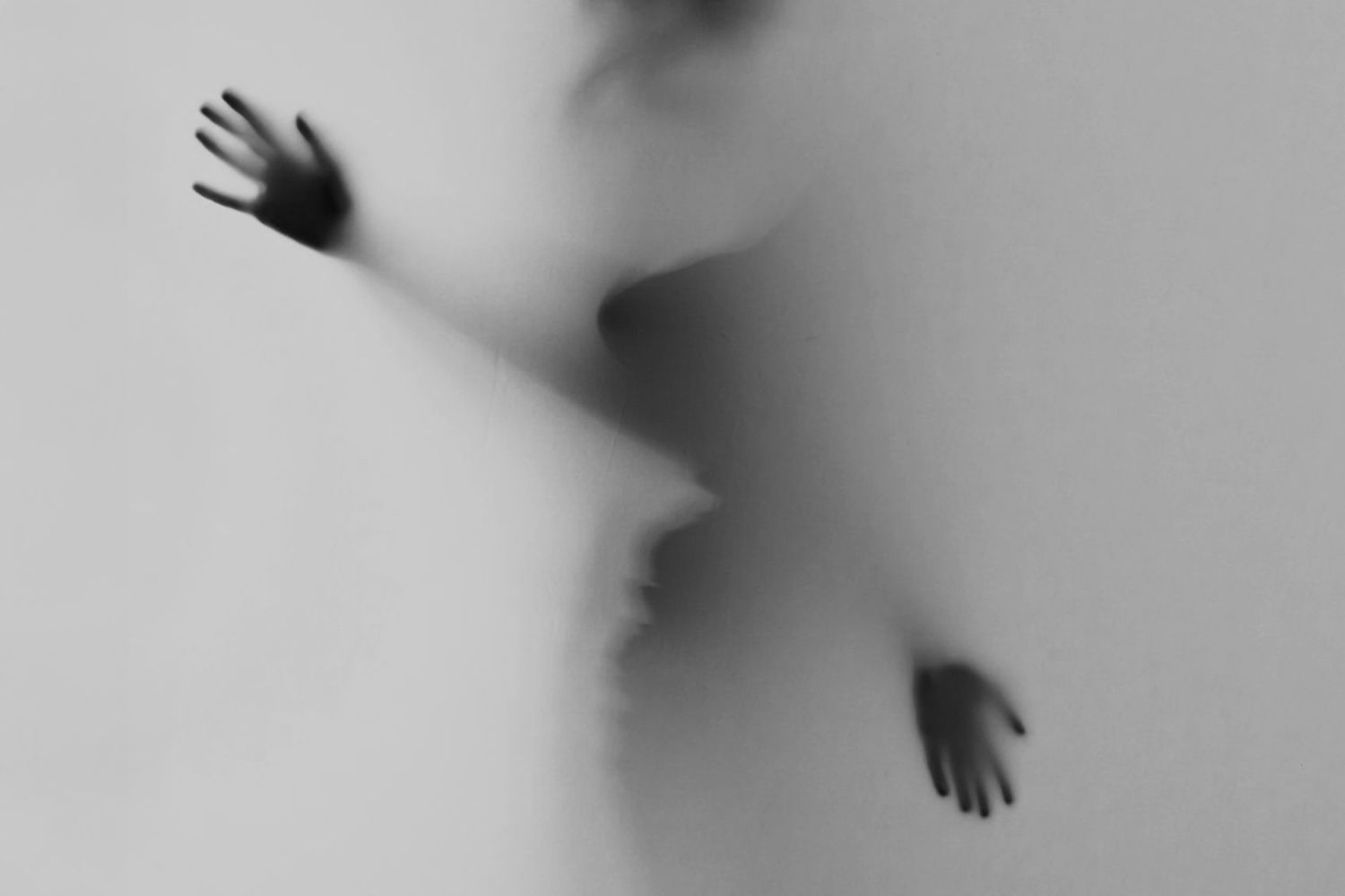 Two hands press against a translucent white fabric creating an eerie silhouette effect, boudoir session Playa del Carmen.