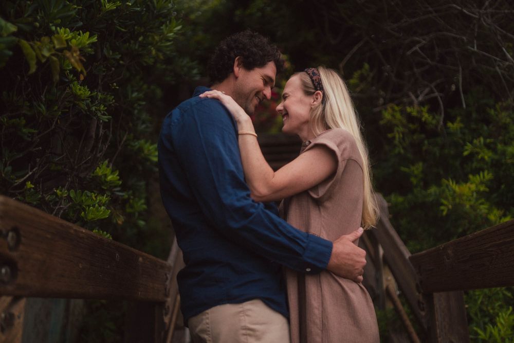 Romantic couple embraces during an outdoor photoshoot in a lush green forest setting.