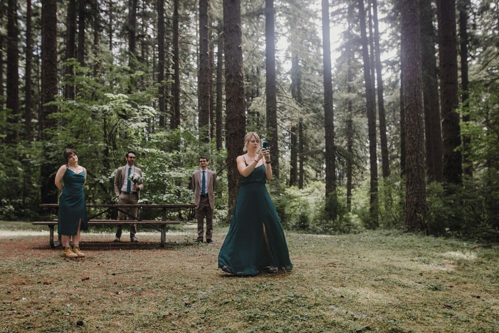 A magical forest wedding ceremony takes place in a misty clearing surrounded by tall evergreen trees.