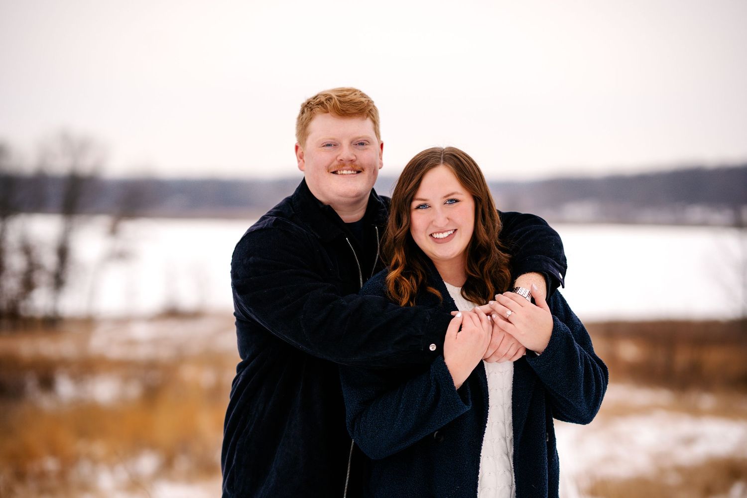 A couple sharing a tender moment while standing in a snowy winter landscape.