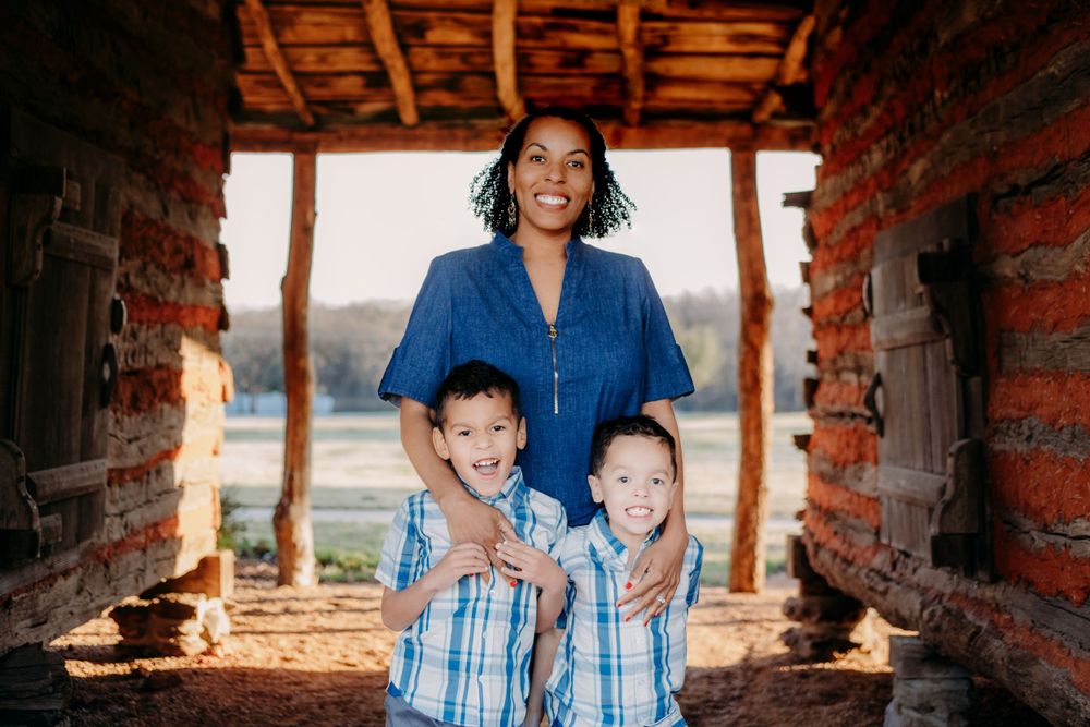 A family smiles together while standing in a rustic brick archway with countryside views in the background.