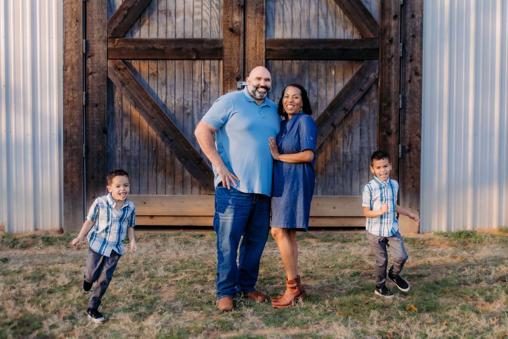 Family posing together in front of rustic wooden barn door.