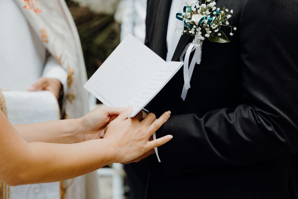 A couple exchanges wedding vows while holding papers, captured by Apertured Media Auckland Wedding Photographer.