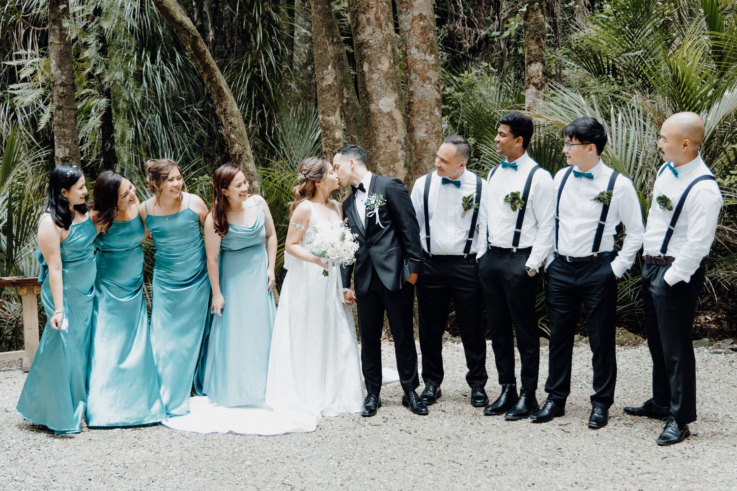 A wedding party cheers the bride and groom as they kiss captured by Apertured Media Auckland Wedding Photographer.