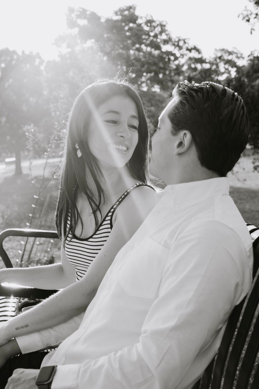Couple shares a tender moment on a park bench in natural sunlight.
