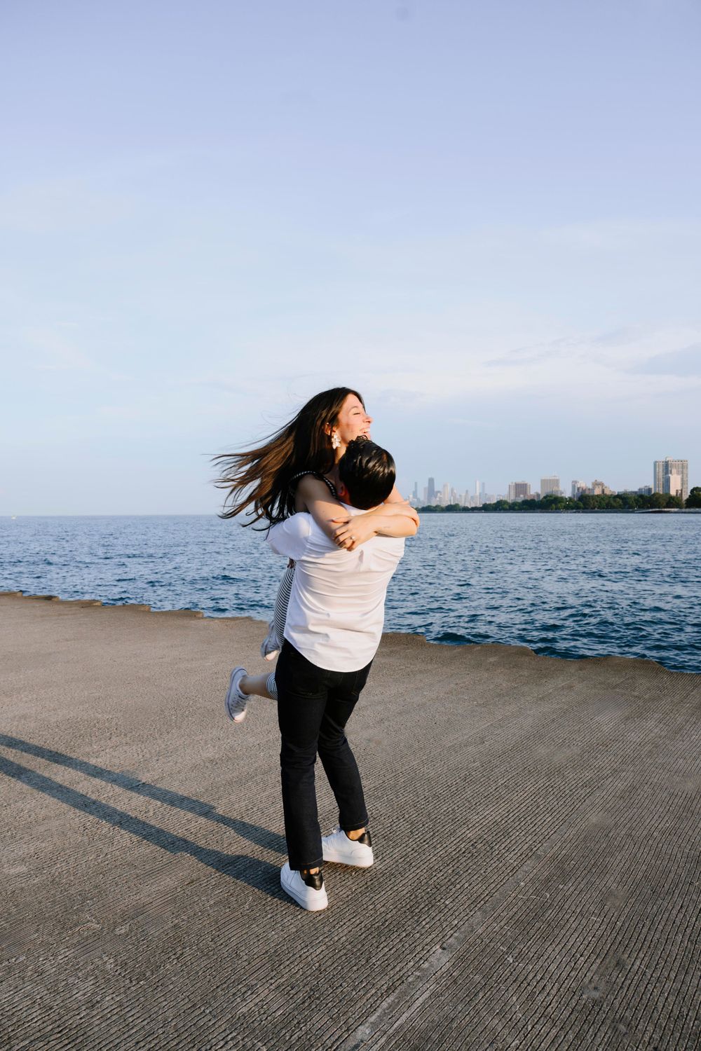 Joyful moment as couple embraces and spins by the waterfront.