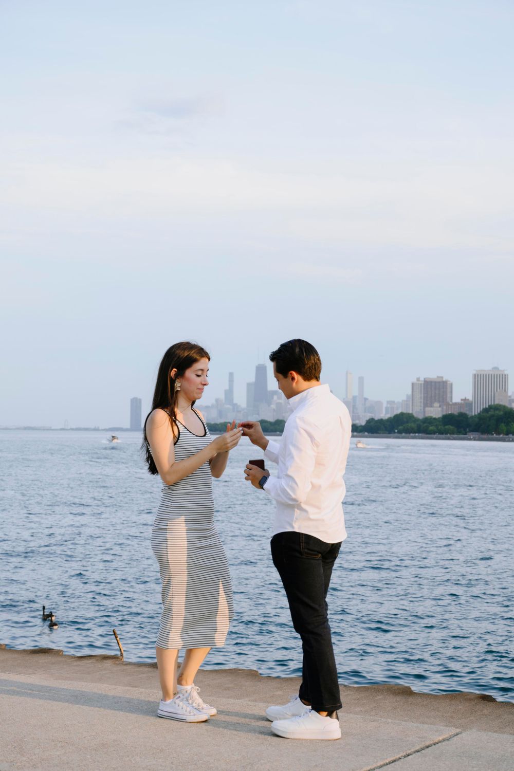 A couple shares a romantic moment by the lakefront with the Chicago skyline in the background.