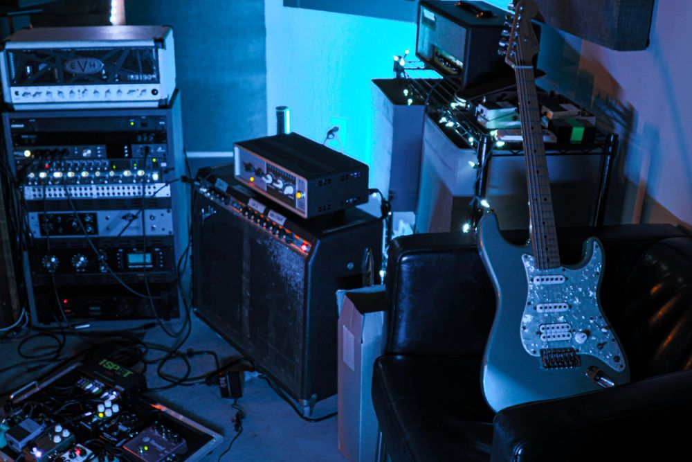 Musical equipment setup with amplifiers and electric guitar in blue stage lighting.