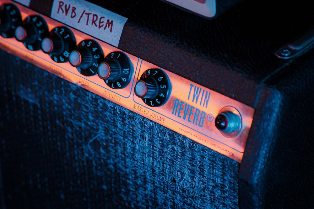 Close-up of an amplifier control panel with knobs and RNS/TREM label in orange lighting.