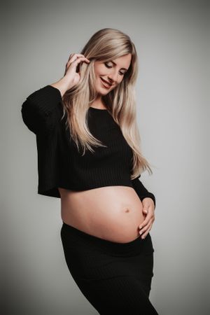 Casual maternity portrait in black sweater and skirt outfit.