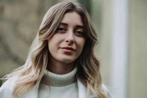 Close-up portrait of woman in cream turtleneck sweater with soft natural lighting.