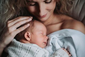 Intimate portrait of mother cradling sleeping newborn.