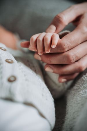 Close-up of tiny baby hand holding parent's finger.