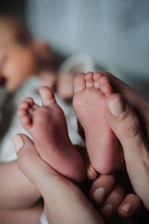 Close-up of baby's tiny feet being held by parent's gentle hands.