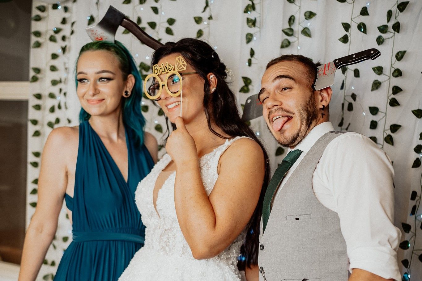 Three friends pose joyfully together with a sparkly curtain backdrop at a wedding celebration.