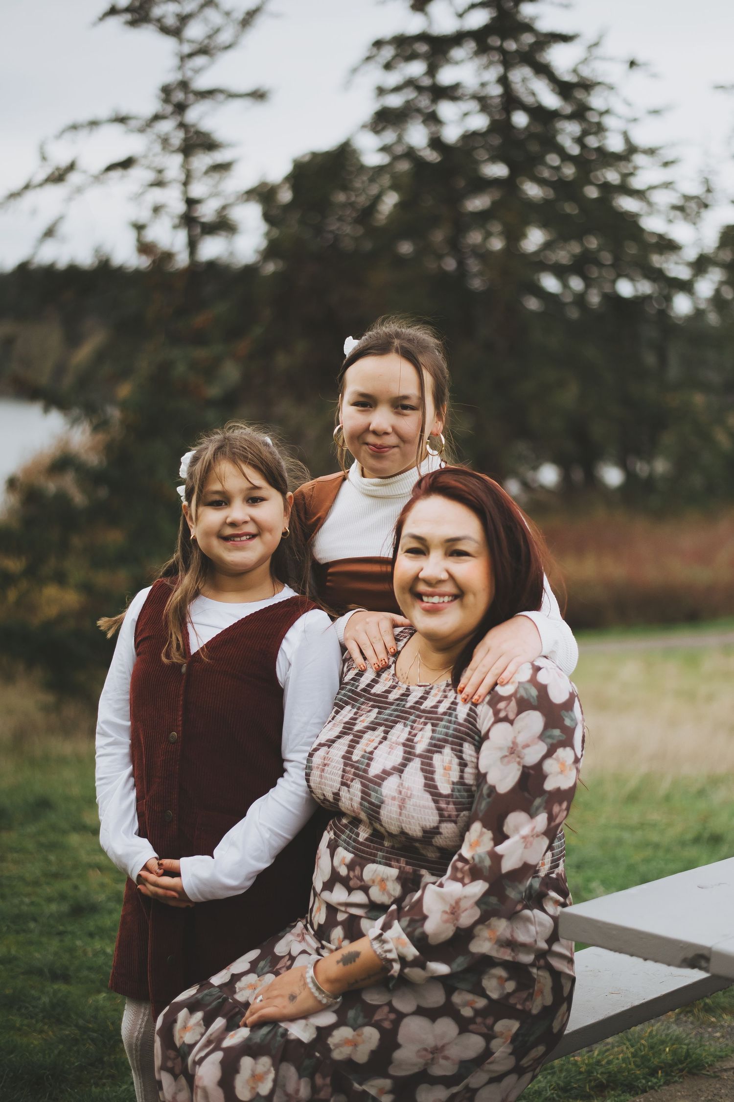 "Mother sitting with her daughters in front of a scenic coastal backdrop.