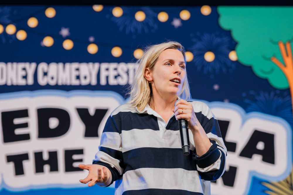 Comedian, Sara Pascoe, performing live on stage at Great Laugh in the Park, Tumbalong Park in Sydney. © SIX84 Photography, Event Photography