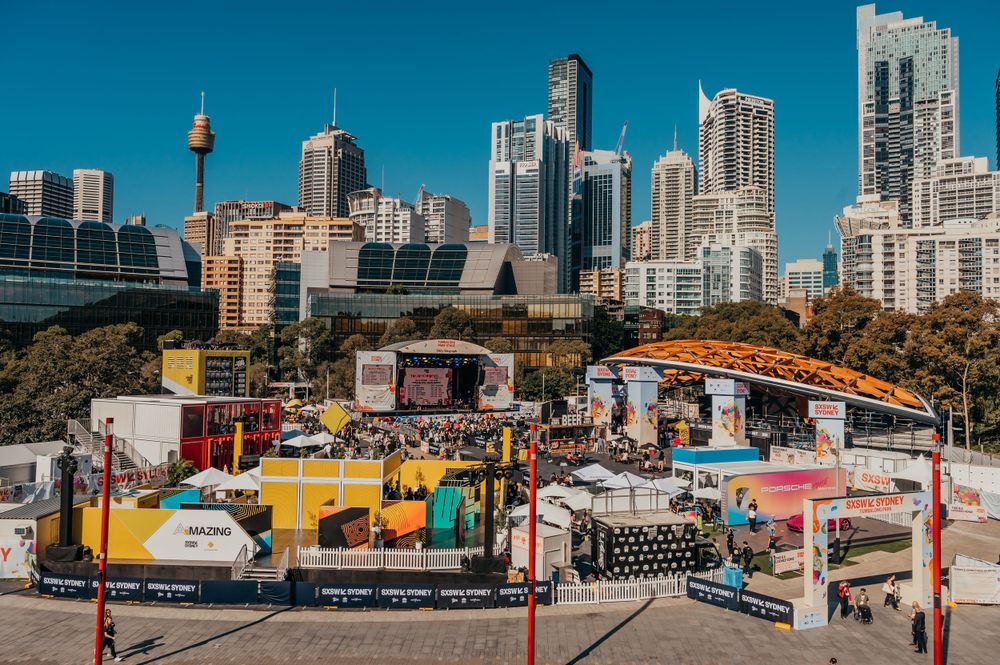 Outdoor festival SXSW setup with stage and vendor booths against Sydney city skyline. SIX84 Photography, Event Photography, Sydney