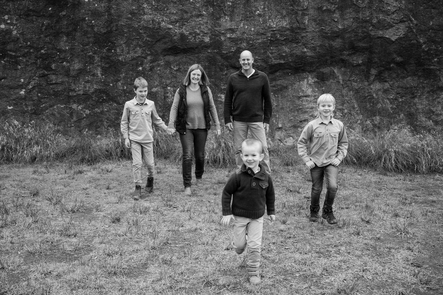 A black and white portrait of a family walking together against a rocky backdrop.