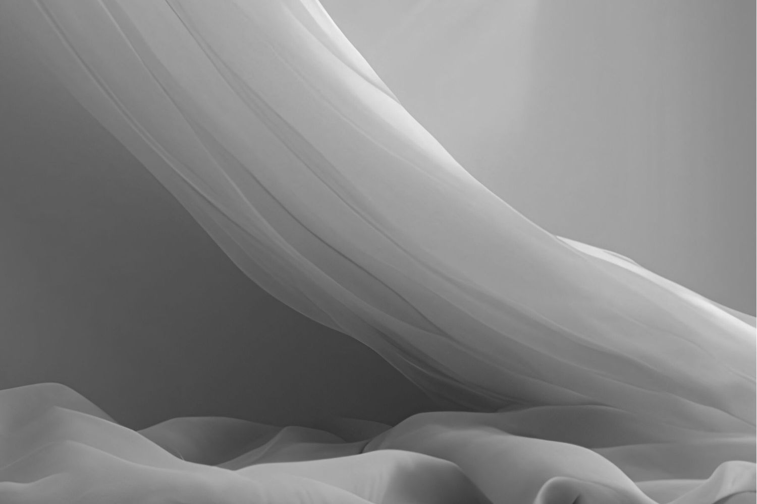 Graceful white flowing fabric creates ethereal waves and curves in monochromatic black and white tones.
