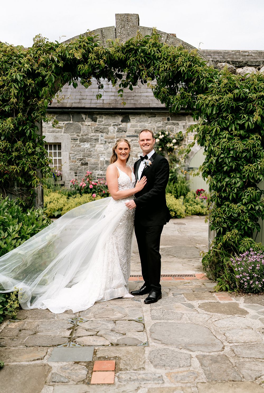 A couple in wedding attire poses together on stone patio steps surrounded by lush greenery in multiple candid shots.
