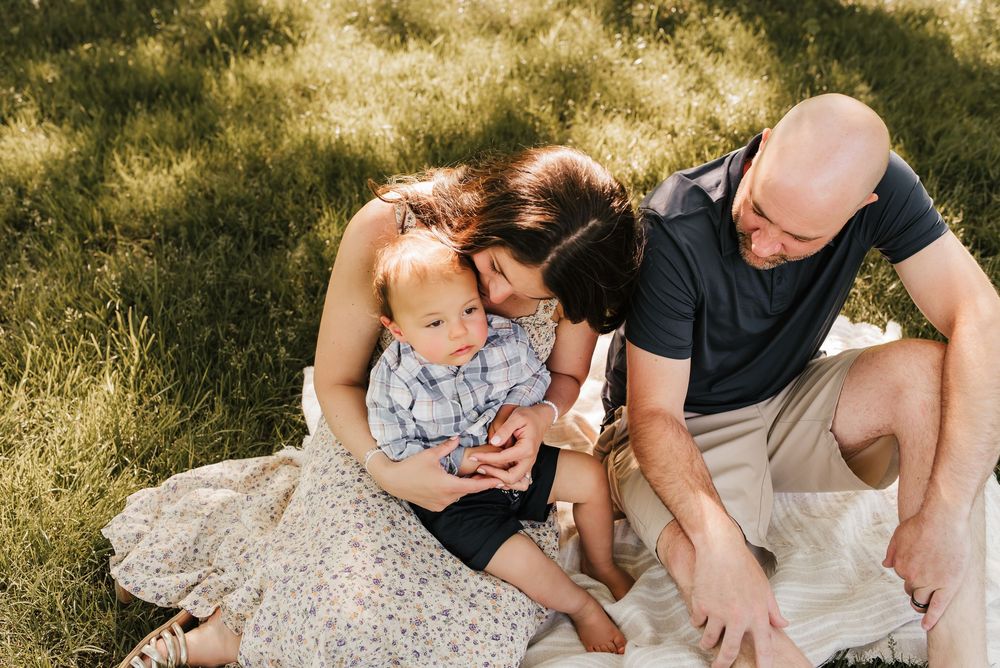 family sits at park and snuggles together