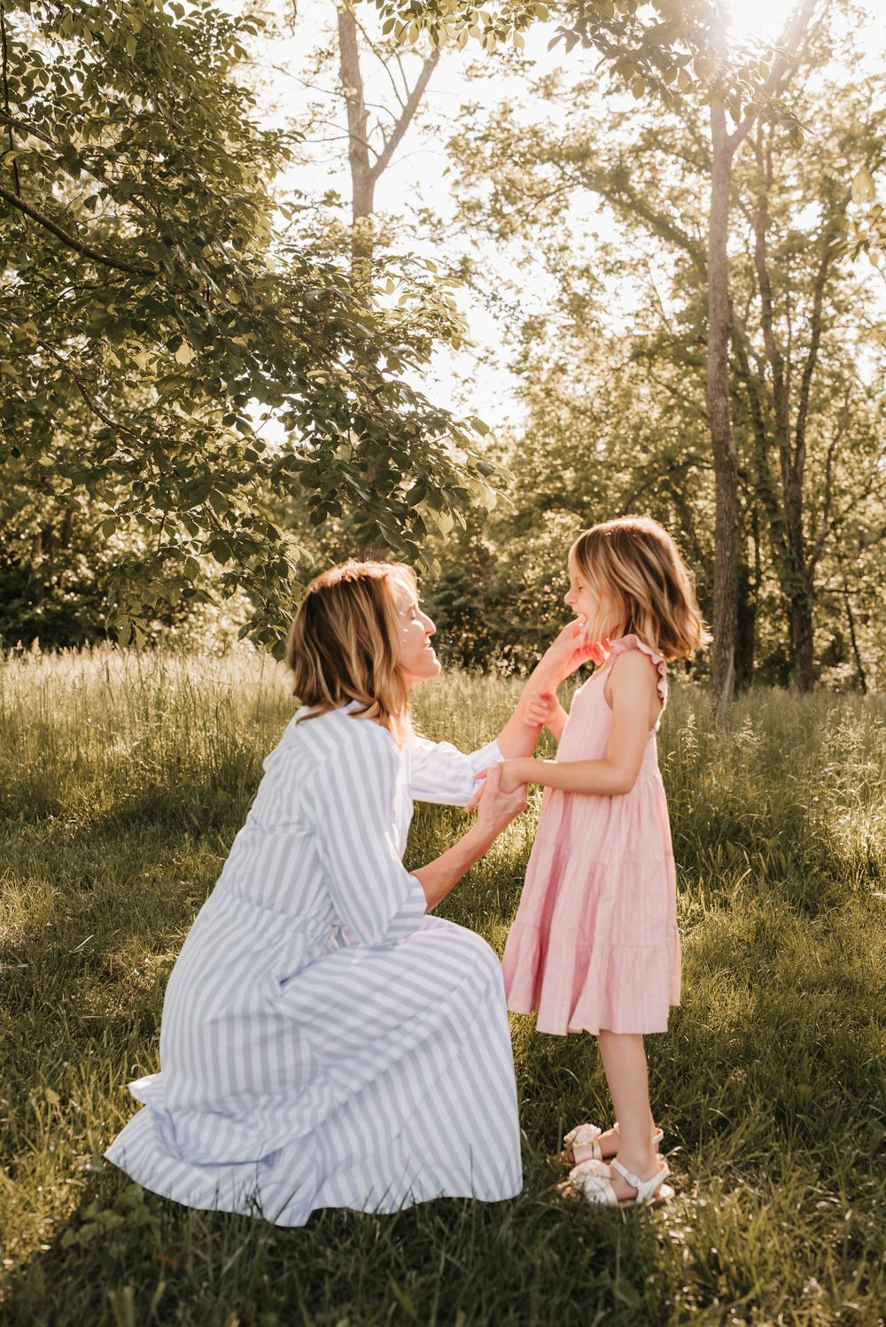 mom kneels by daughter and pushes hair out of her face