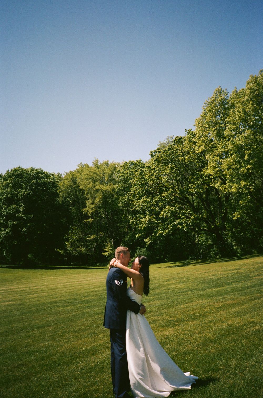 A bride and groom dancing together on their wedding day in a scenic outdoor setting.