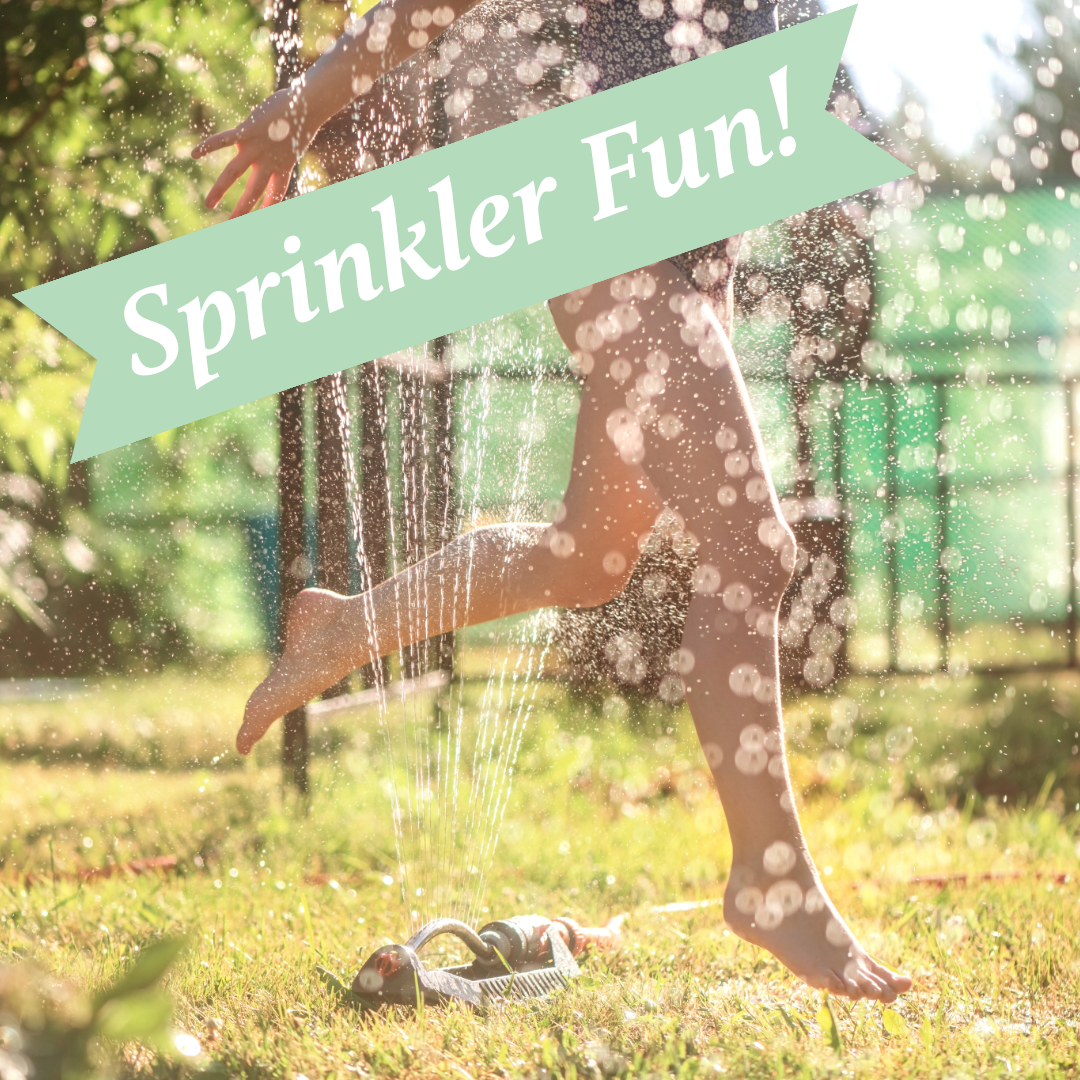 A silhouette playing in backyard sprinklers on a sunny summer day with sparkling water droplets in the air.