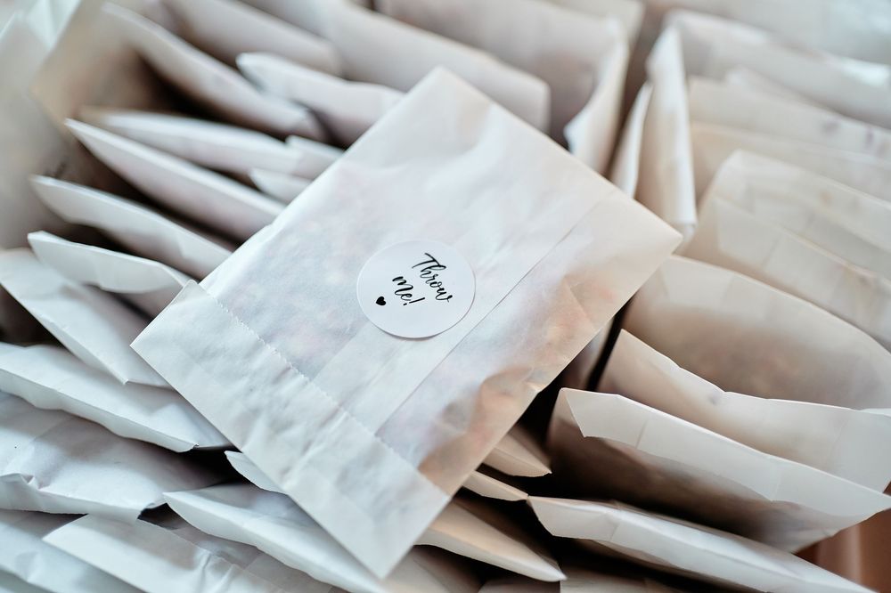 Small white paper favor bags with heart stickers arranged in neat rows on a light surface.