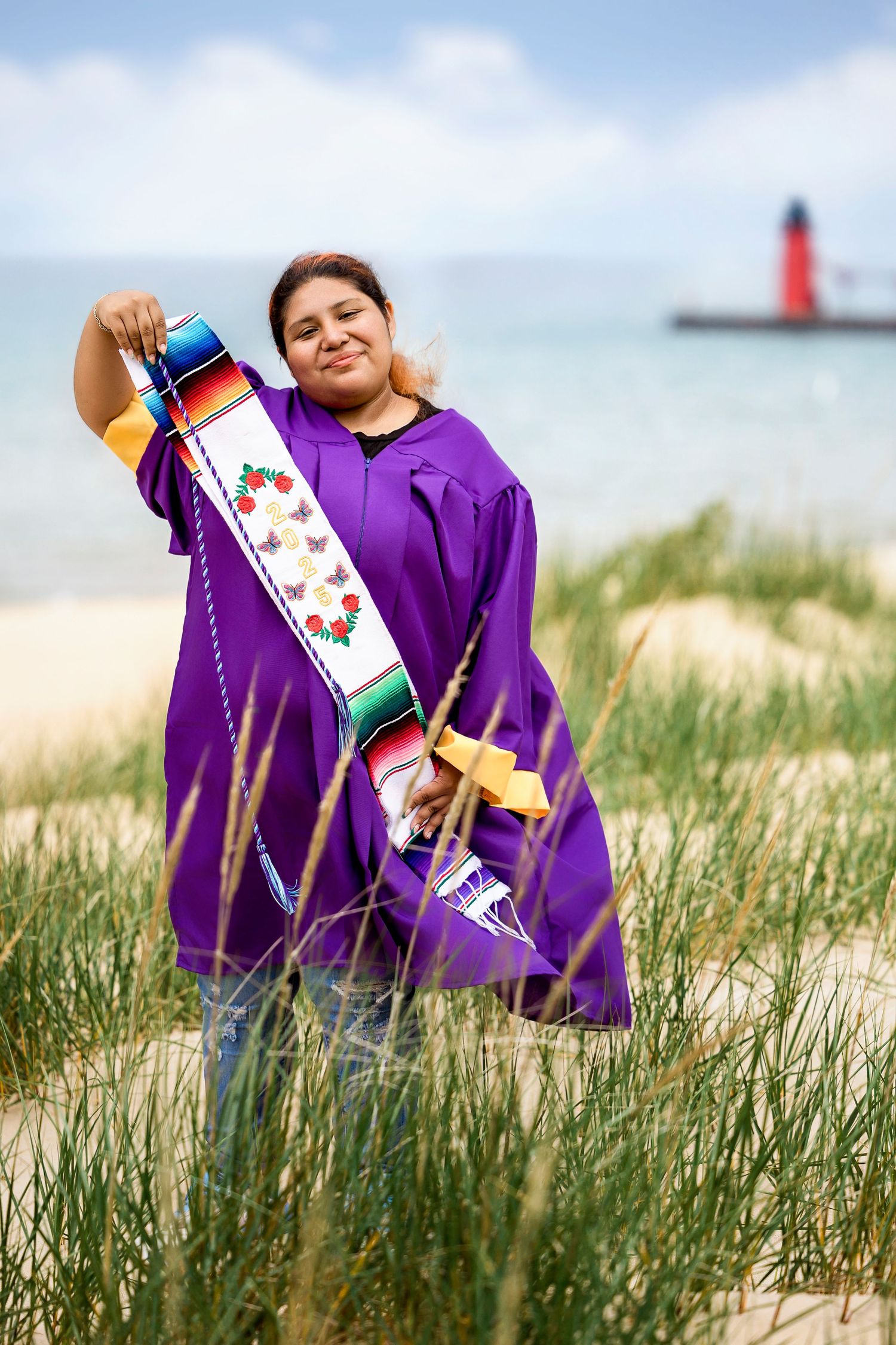 A senior photo that shows Alejandra walking a trail through beach grass in South Haven, with the breeze catching her gown just slightly.