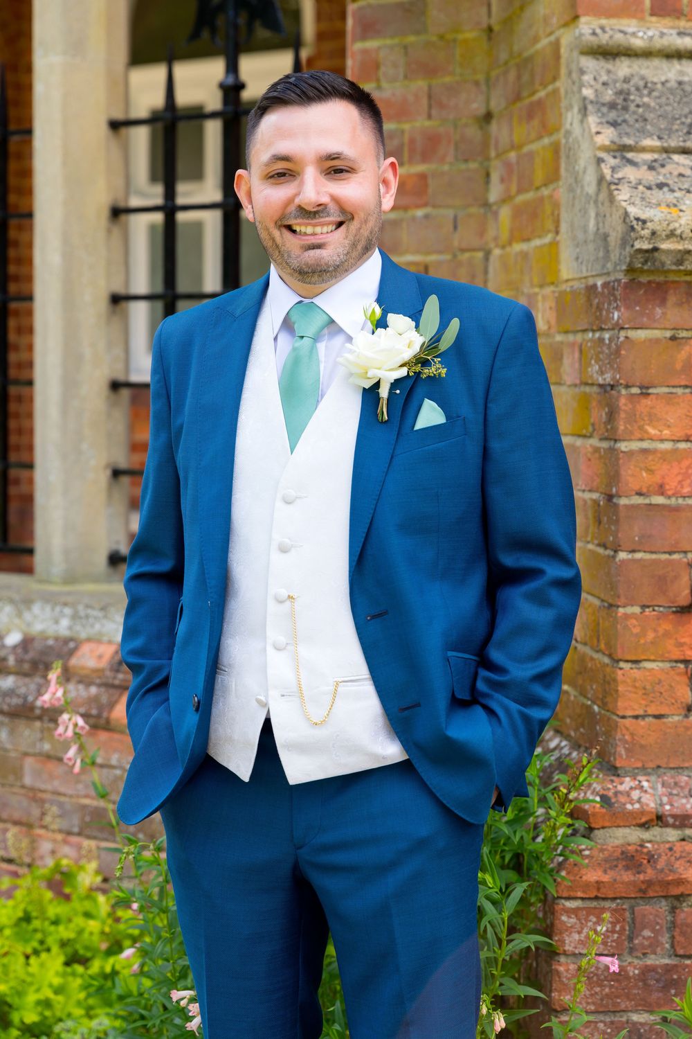Portrait of Alan smiling in his suit outside Audley’s Wood Hotel on his wedding day.