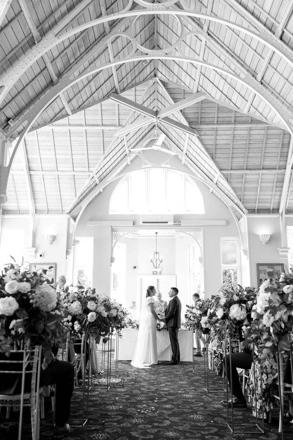 Black and white view of the wedding ceremony inside the grand hall at Audley’s Wood Hotel.