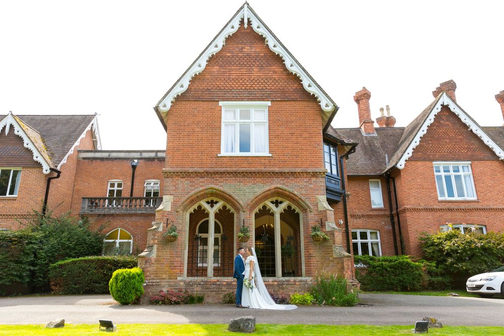 Bride and groom standing under gothic arches of Audley's Wood Hotel