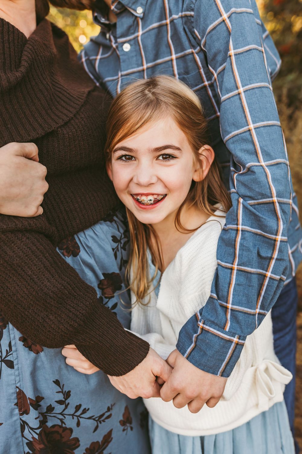 Close up portrait of person in white sweater and blue dress during autumn photo session.