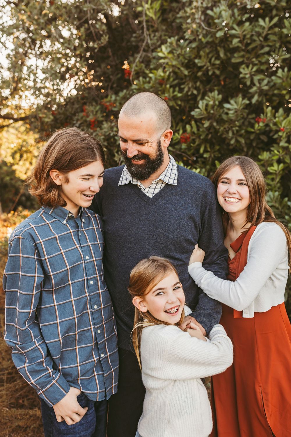 A joyful family shares candid laughter while posing together on a nature trail during sunset.