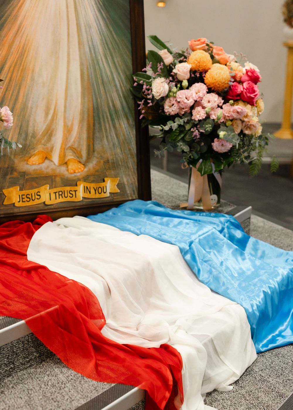 Colorful floral arrangement with Jesus sign next to red, white and blue fabric display.