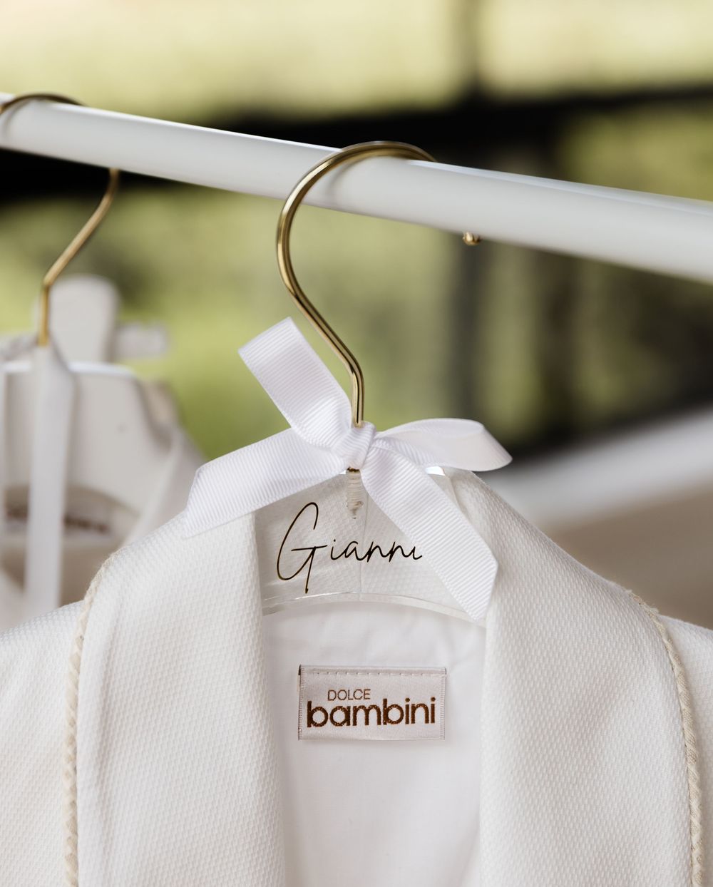 White baby clothing hanger with Gianni name tag and bambini brand label on display.