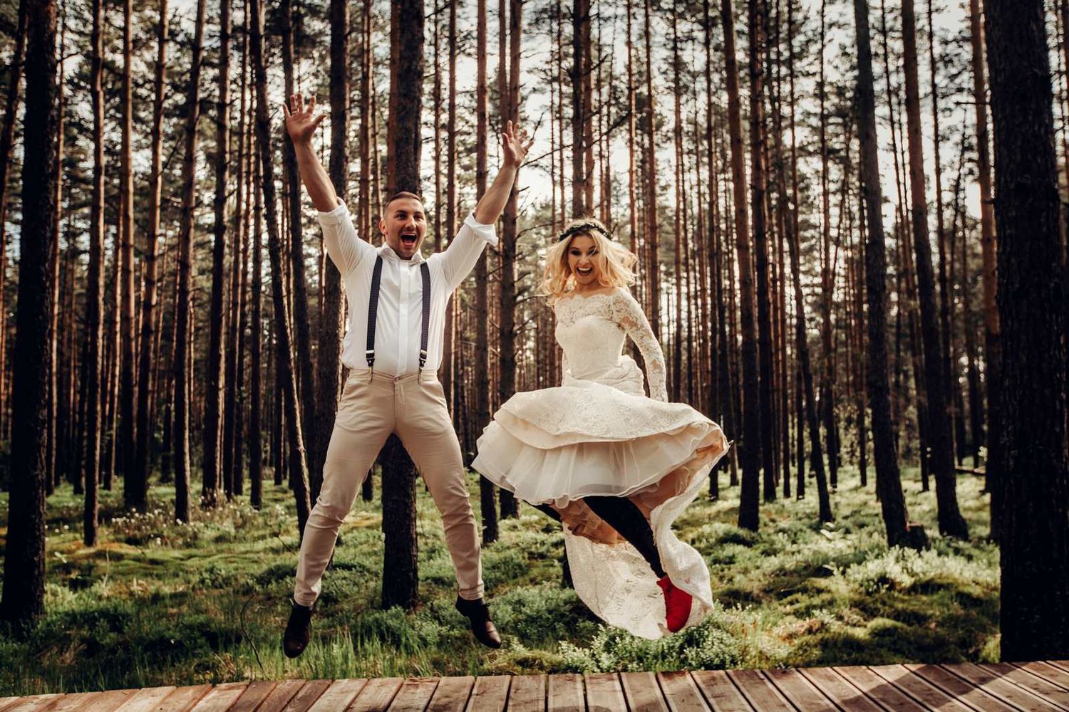 Sesja ślubna na torfowisku - Para młoda skacze w lesie na drewnianej kładce