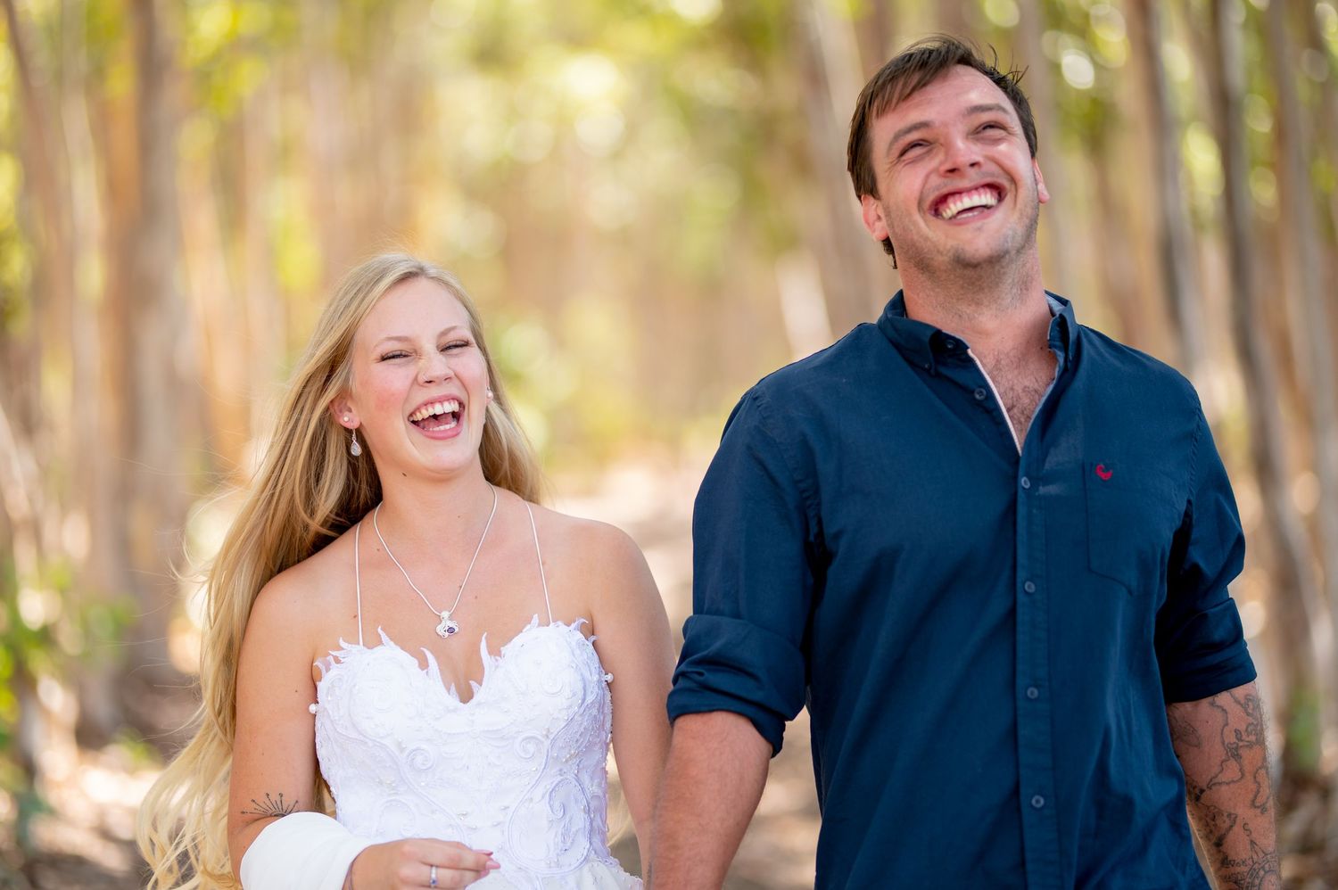 Joyful couple shares a candid laughing moment in a forest setting.