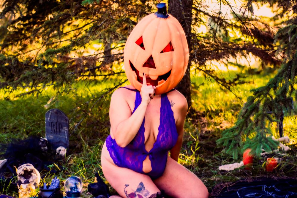 Spooky Halloween setup with lit pumpkin and purple decorative elements in outdoor setting.