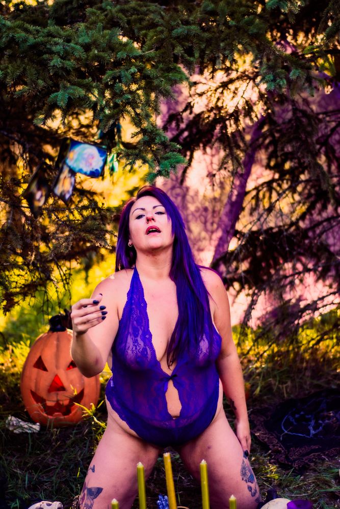 Moody Halloween scene with glowing jack-o-lantern and purple lighting in forest setting.