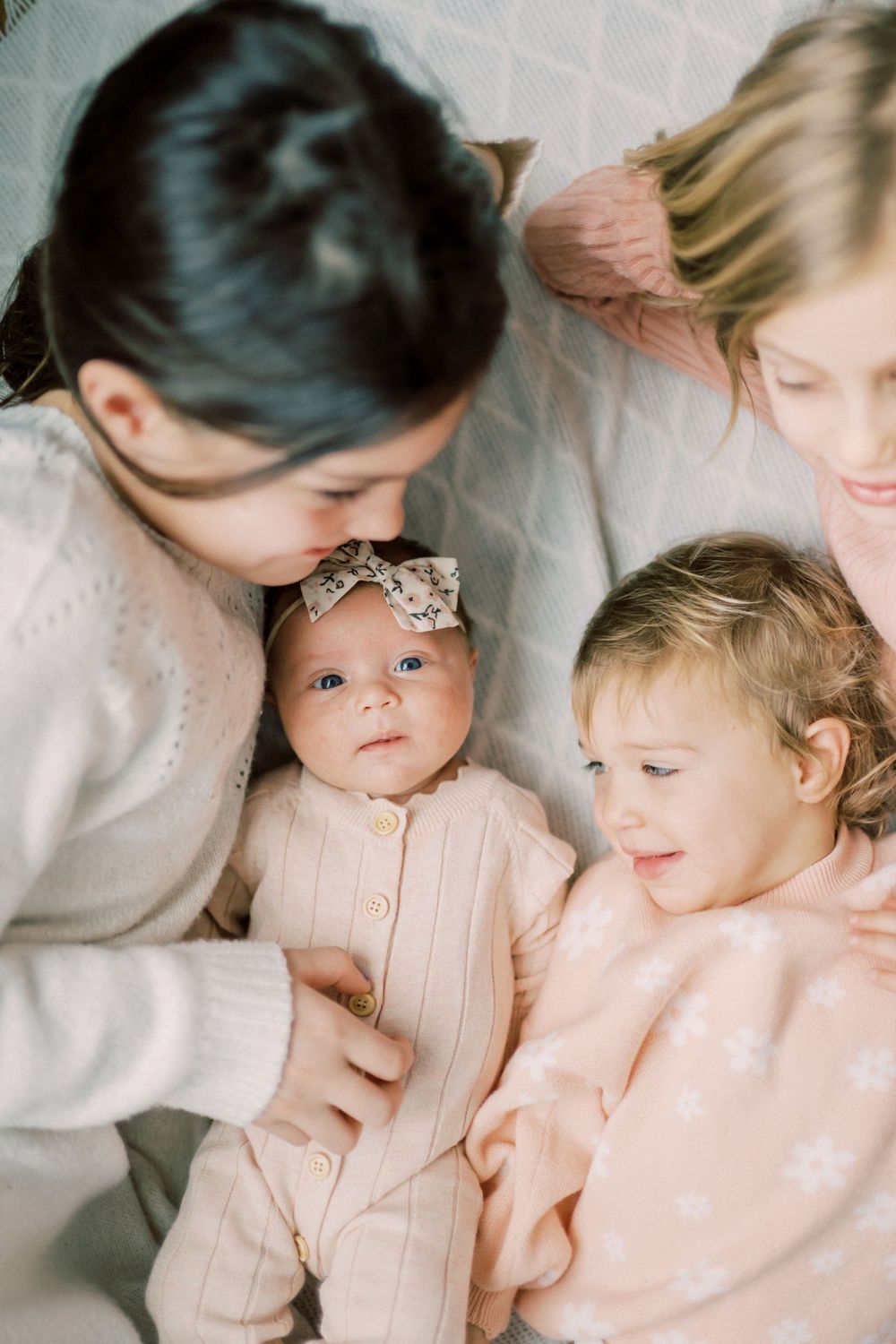 Intimate family portrait with baby in headbow and toddler in soft winter clothing.