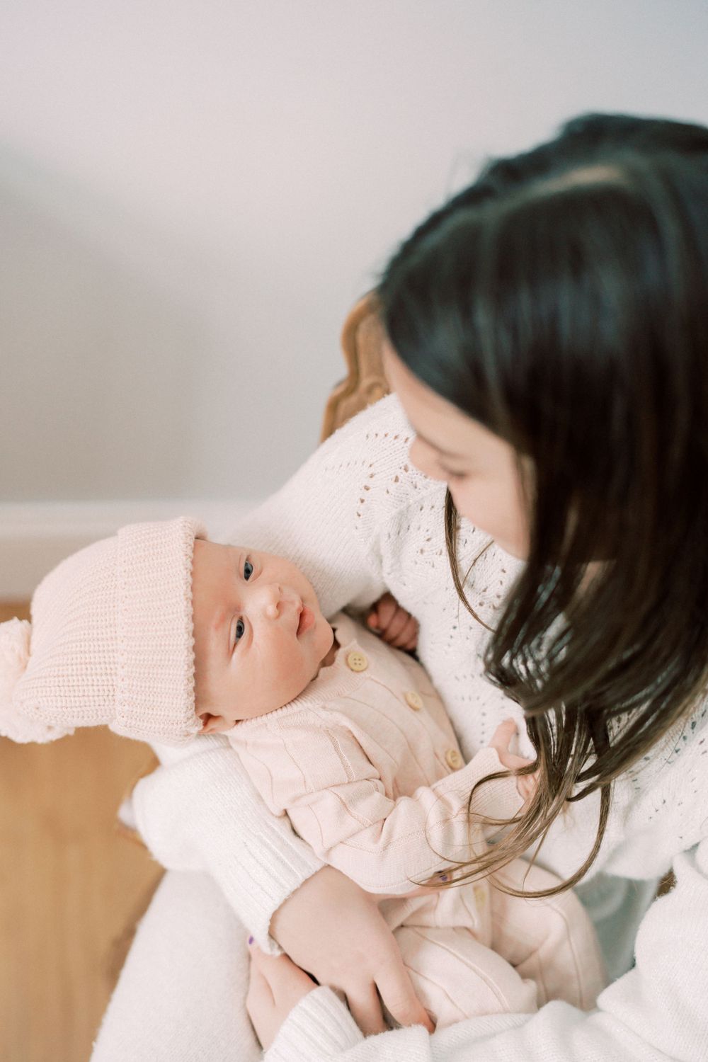 A sweet moment between parent and infant wearing soft pink knit clothing.