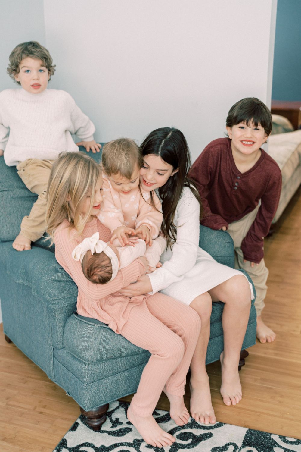 Family gathering on blue couch with children in cozy winter sweaters.